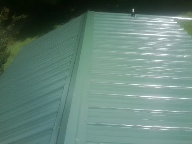 New green metal panels meeting at the ridge of a roof — Flat Roof Repair work by our crew in Oxnard