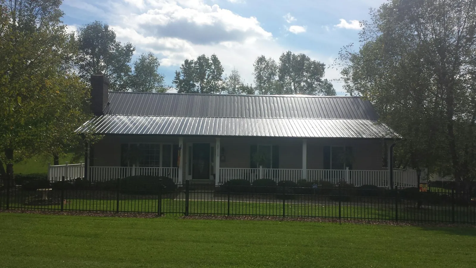 Gray metal roof on a brick ranch with a full width front porch — Gutter Guard Installation work by our crew in Oxnard