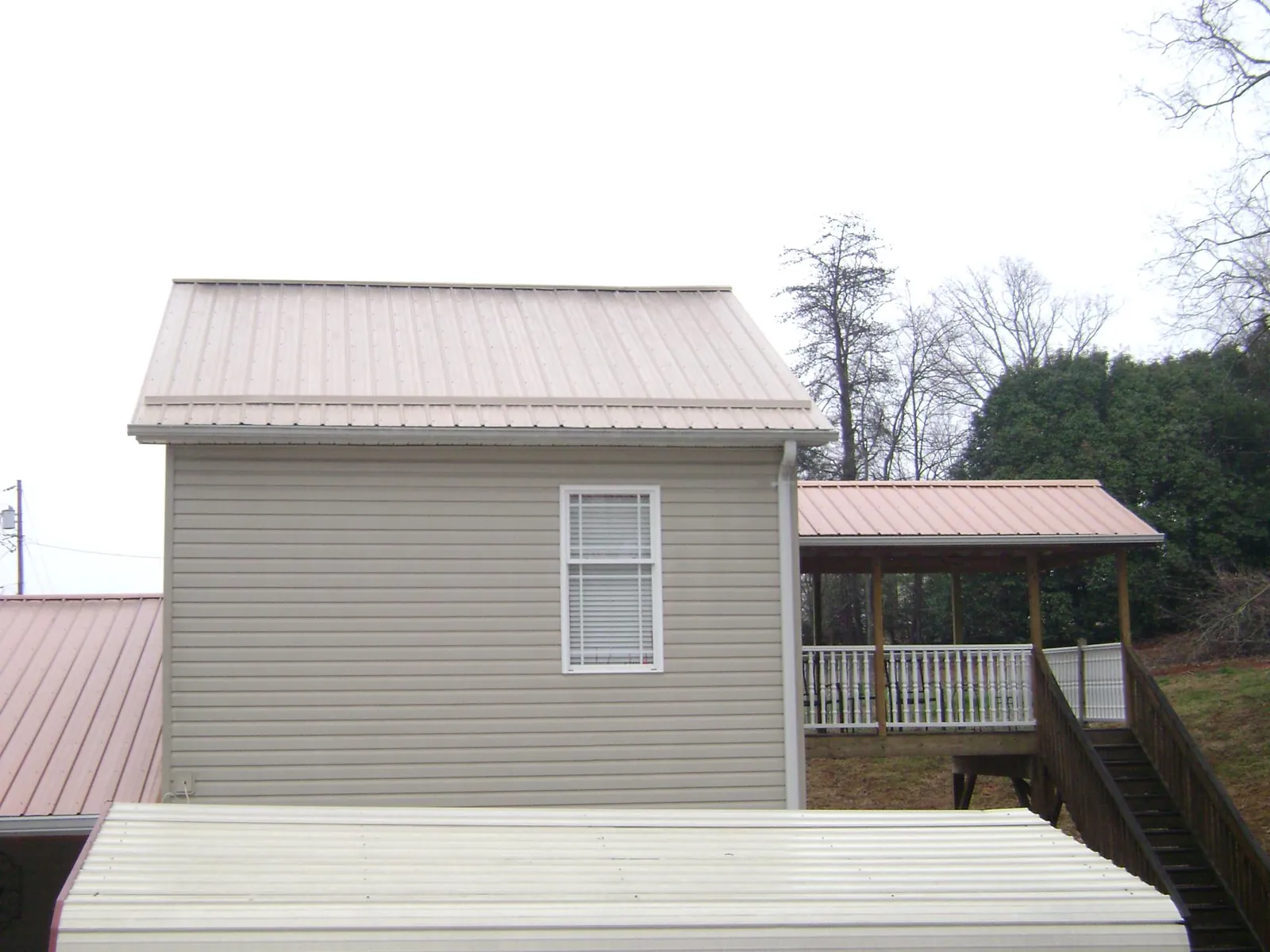 Tan metal roofs on a two story addition and attached porch, from a Roof Replacement job in Oxnard