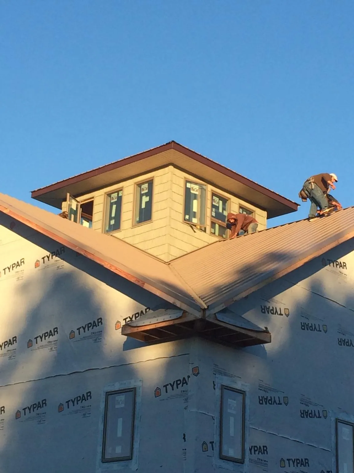 Roofers working around a rooftop cupola on a new metal roof at sunset — Roof Waterproofing in Oxnard by Roofing Brothers